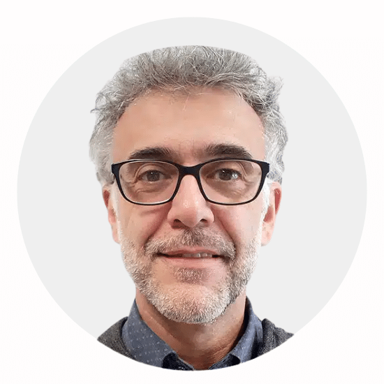 Portrait of a middle-aged man with gray hair and glasses, smiling, circular cropped.